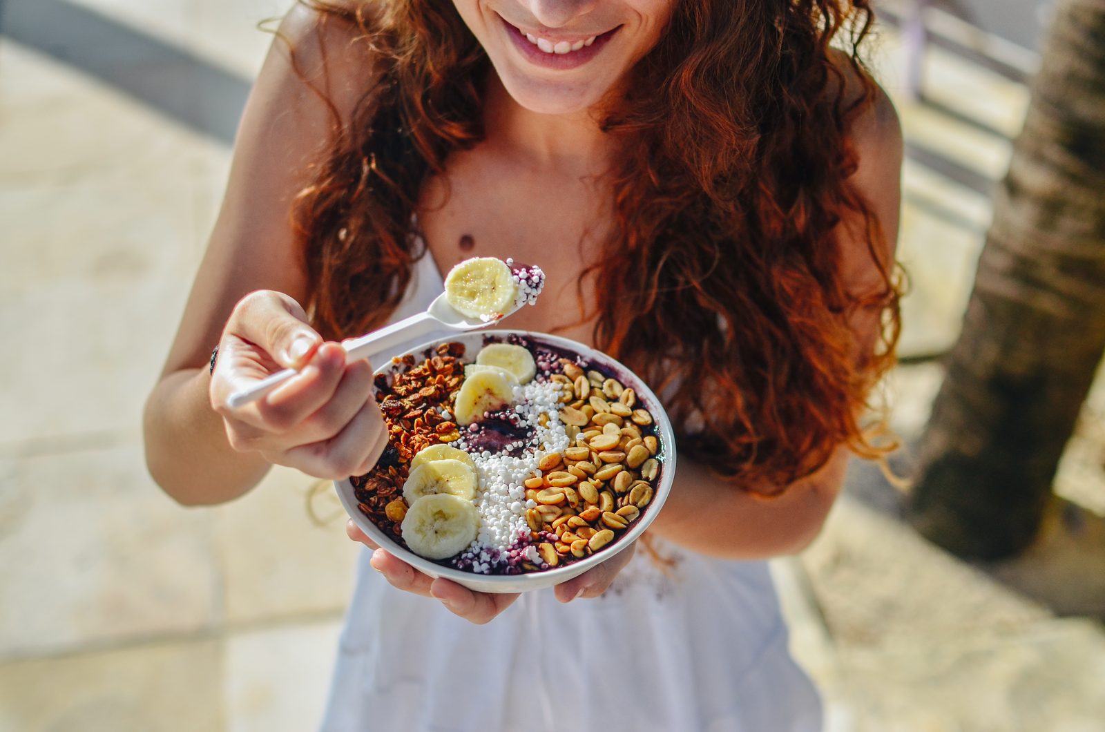 Cliente saboreando um bowl de açaí Triboo com granola e frutas